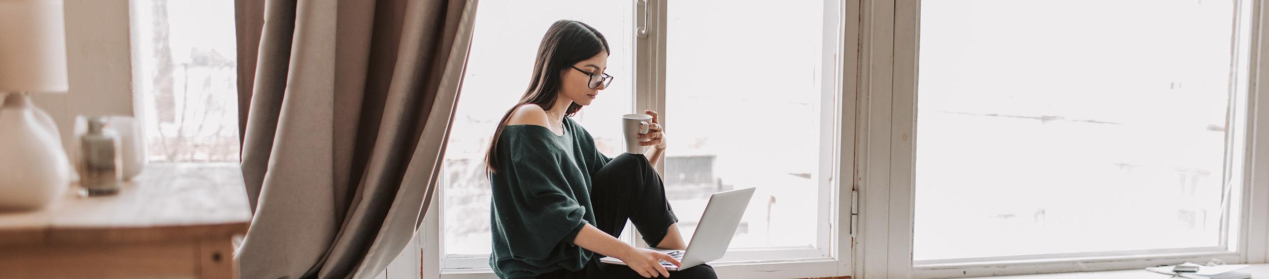 young woman using laptop near a window